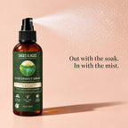 Bottle of rice water hair spray giving off a fine mist against a pink background. Out with the soak. In with the mist.