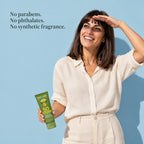 A smiling woman shades her eyes from the sun, holding the tube of SPF 50 mineral sunscreen lotion. No parabens. No phthalates. No synthetic fragrance.