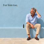 A grey-haired man sits on a ledge by a blue wall with a hand in his hair, the spray bottle beside him. For him too.