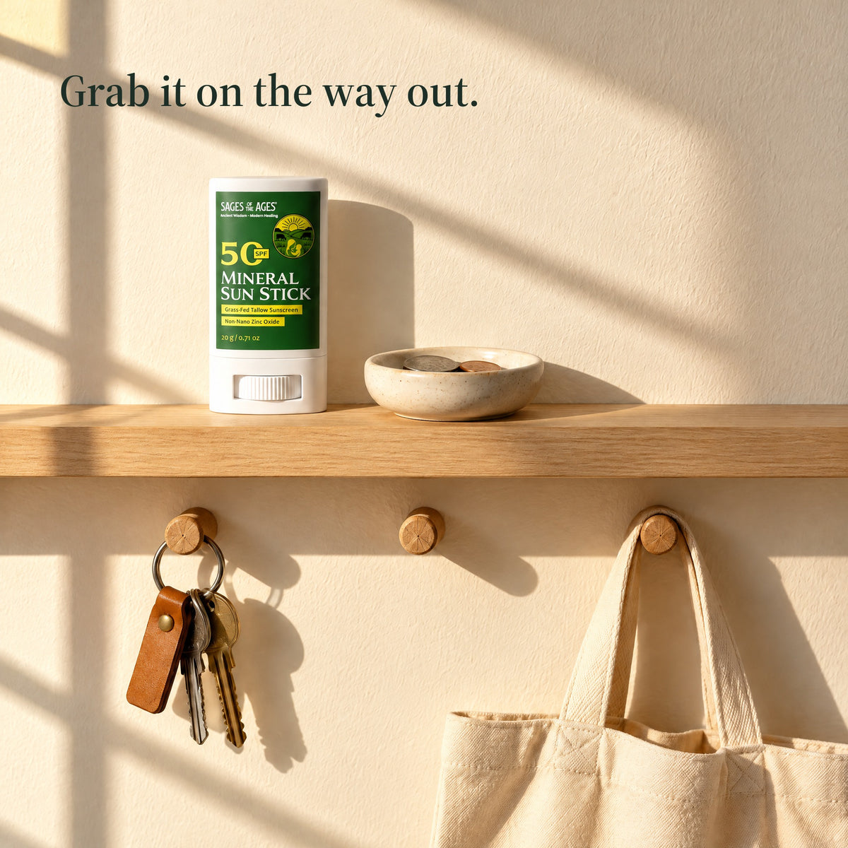 SPF 50 mineral sun stick on a hallway shelf above hanging keys and a tote bag. Grab it on the way out.