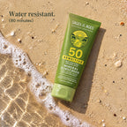 Tube of SPF 50 mineral sunscreen lotion lying on wet sand at the edge of a wave. Water resistant. 80 minutes.