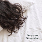 Dark wavy hair spread across white bed linen. No grease. No residue.
