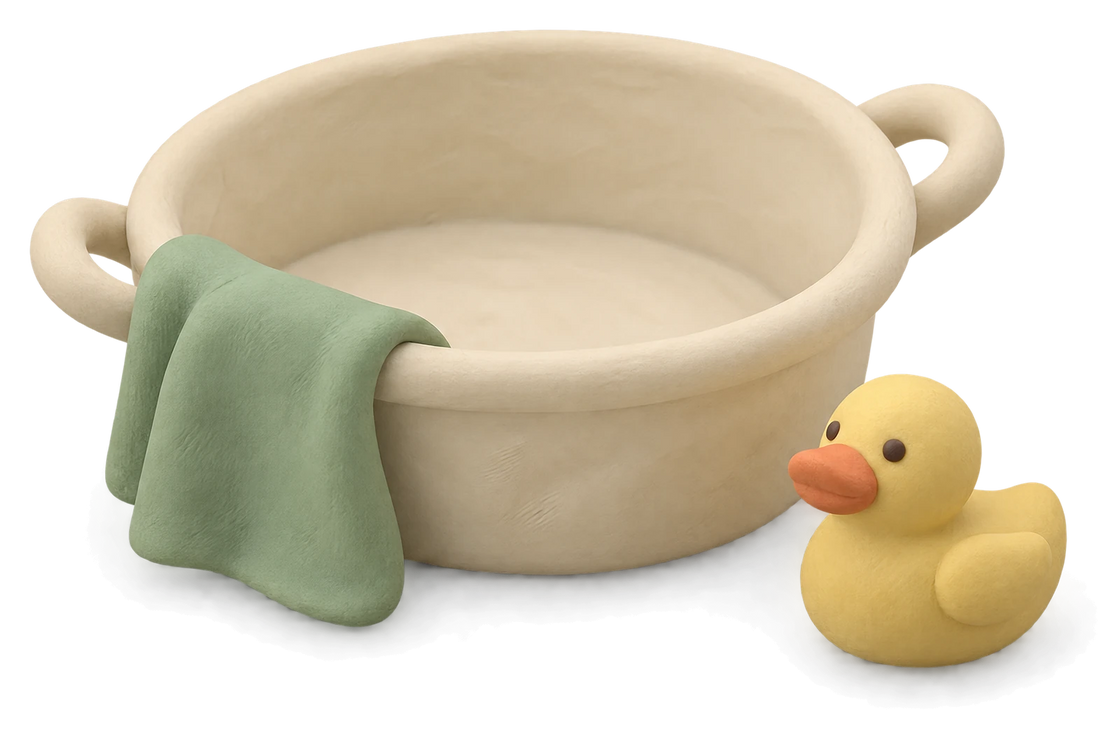 A cream clay wash tub with a green cloth over its rim and a yellow duck beside it